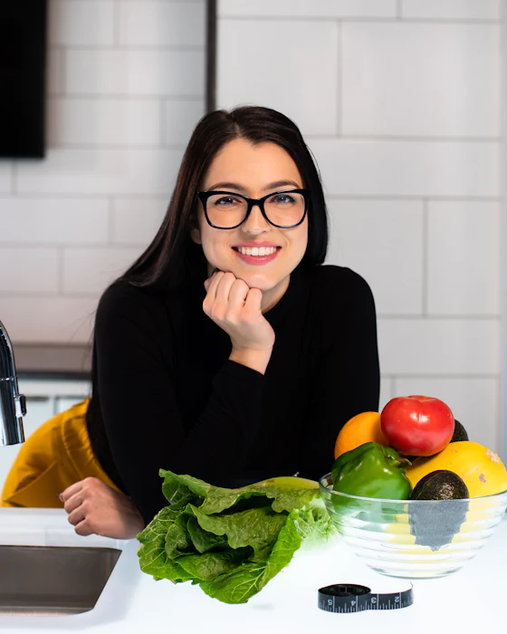 Nutricionista sorrindo ao lado de frutas e legumes